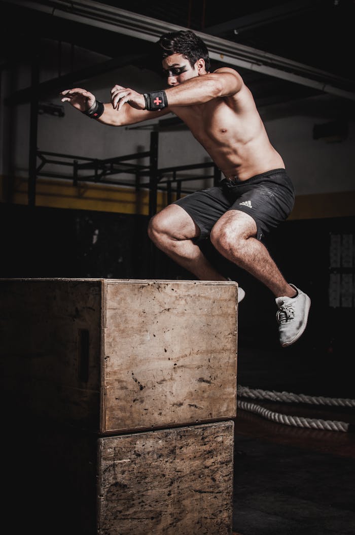 Mastering the First Impression: Your intriguing post title goes here Shirtless man showcasing strength and fitness with a box jump in an indoor gym setting.